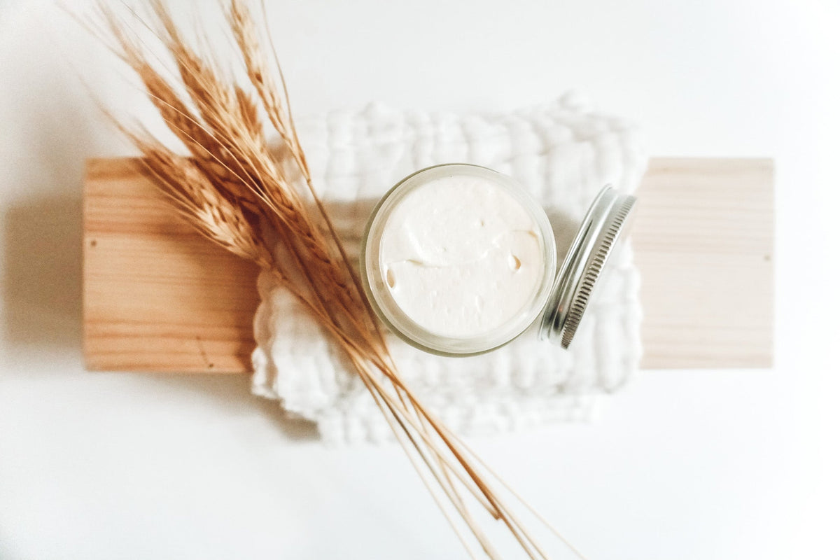 White tin of body powder cream with comb and dried stems on folded muslin cloth