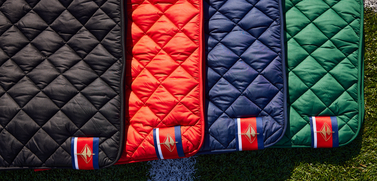 Quilted puffer blanket colors: black, red, navy, and green with logo patch