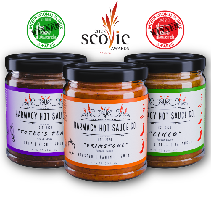 Three hot sauce jars with colorful labels and black lids