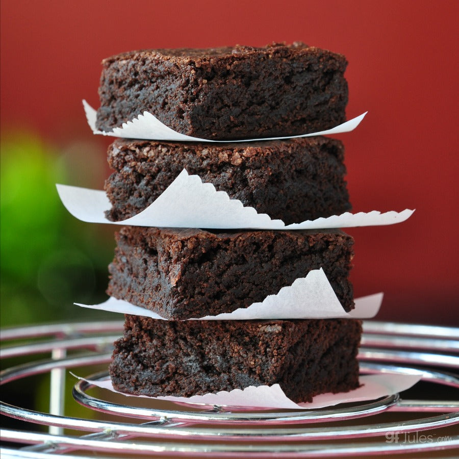 Gluten-free flour brownies, stacked dark pieces on a plate with parchment strips