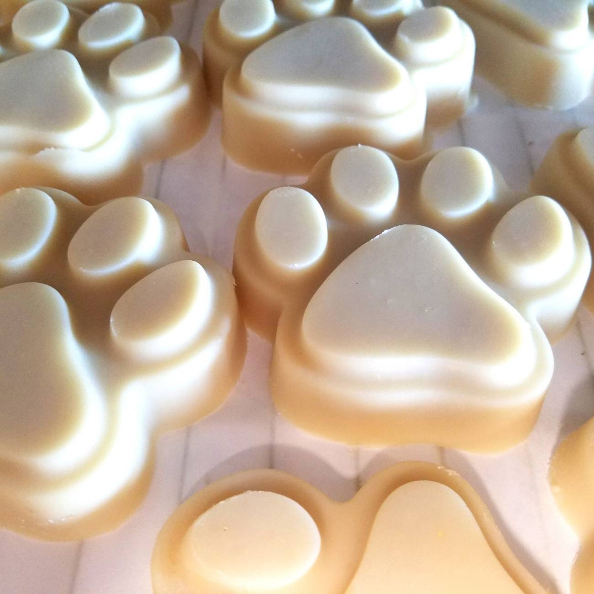 Multiple paw-shaped goat milk soap bars lined in tray, light cream color