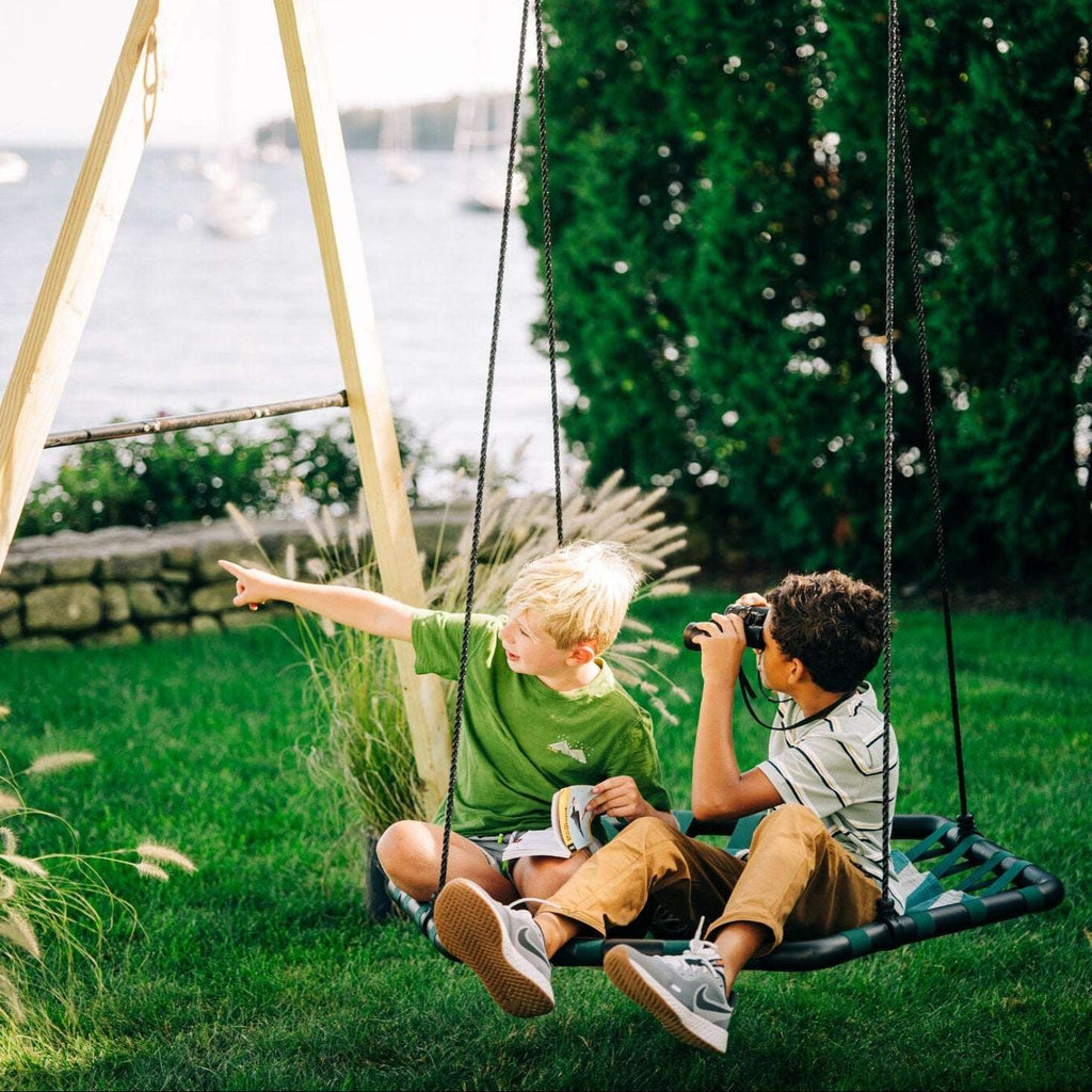 Children's rope swing with green frame, woven seat, and hanging chains outdoors