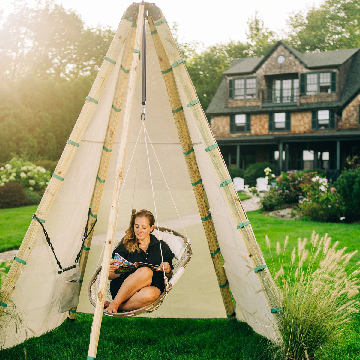 Wood-framed outdoor teepee with canvas panels and hanging rope