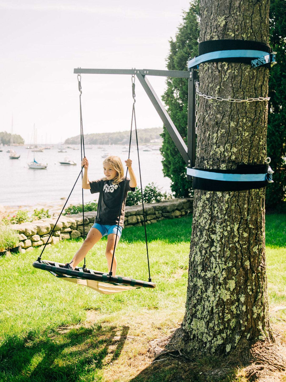 Children's rope swing tied to a tree trunk with hanging ropes and woven seat