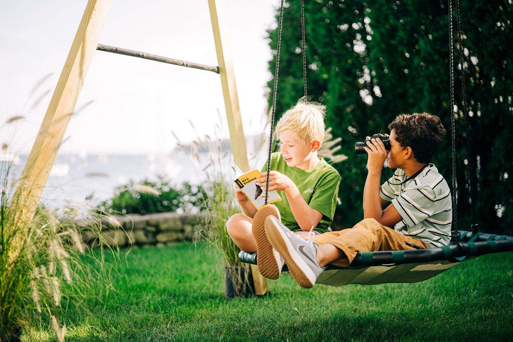 Kids sitting on a green rope swing with woven seat and hanging support cords