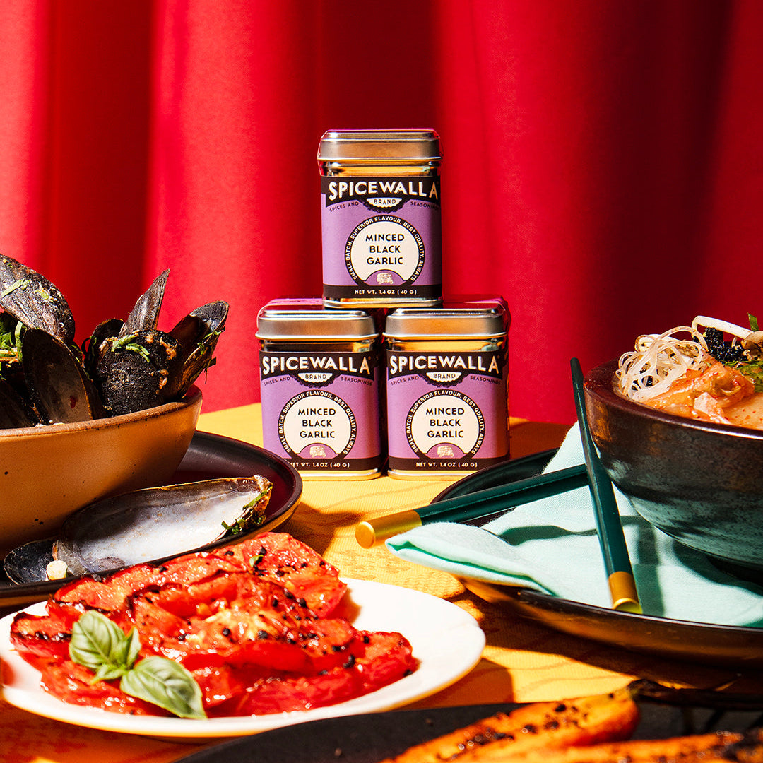 Spicewala minced black garlic jars on a table with bowls of food