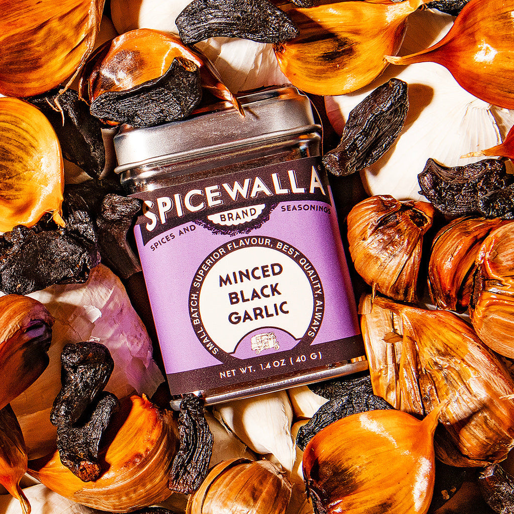 Spicewala minced black garlic seasoning jar surrounded by garlic cloves