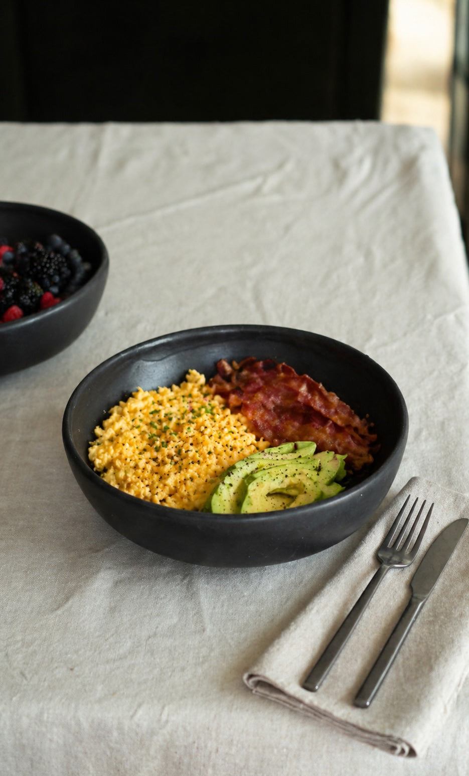 Black matte stoneware pasta bowl with prepared pasta and avocado slice