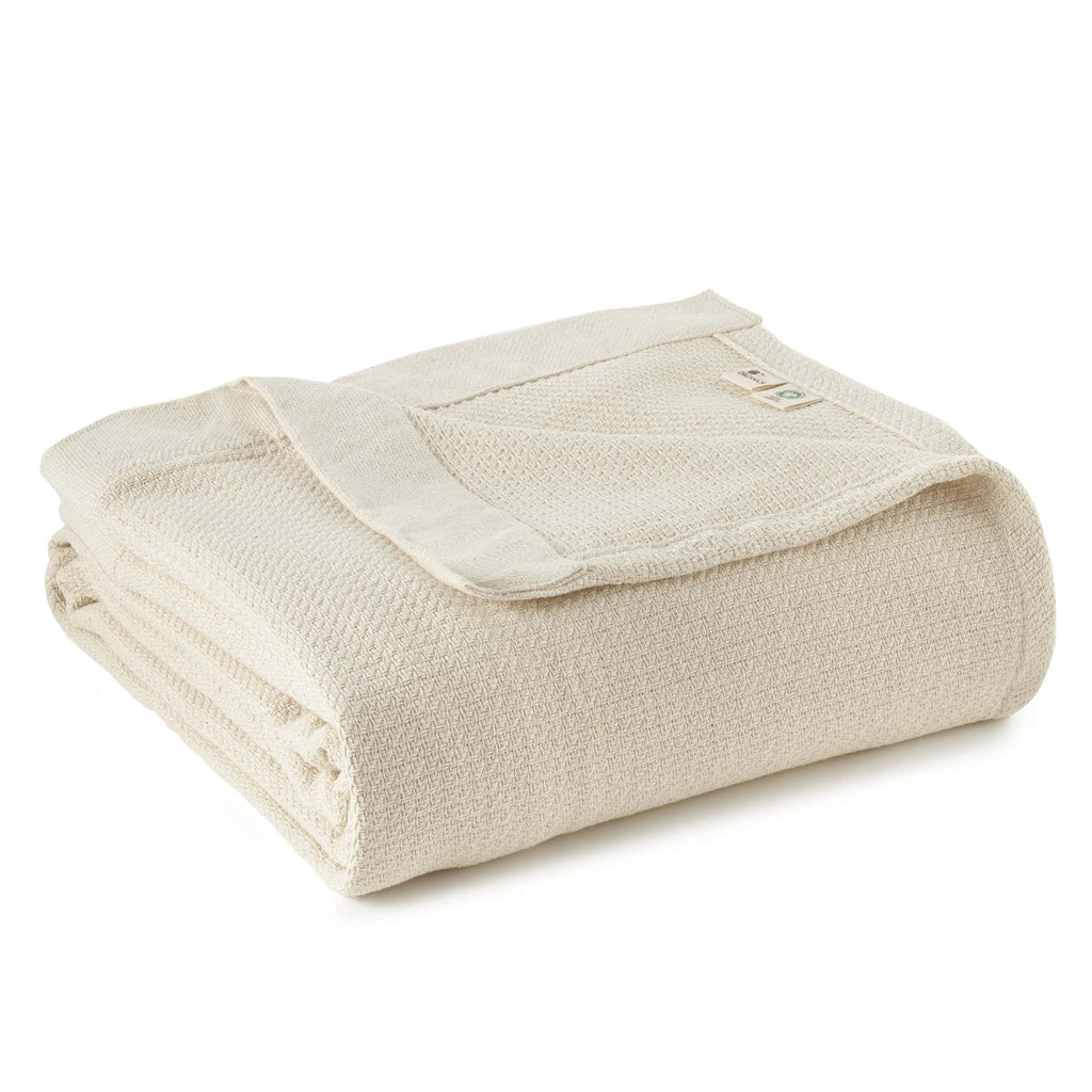 Natural woven blanket folded with textured weave and stitched edge.