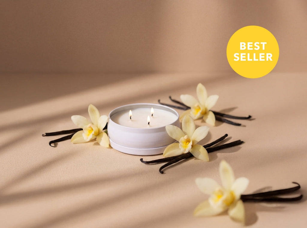 White 3-wick candle in shallow jar with orchid flowers and dark wood stems