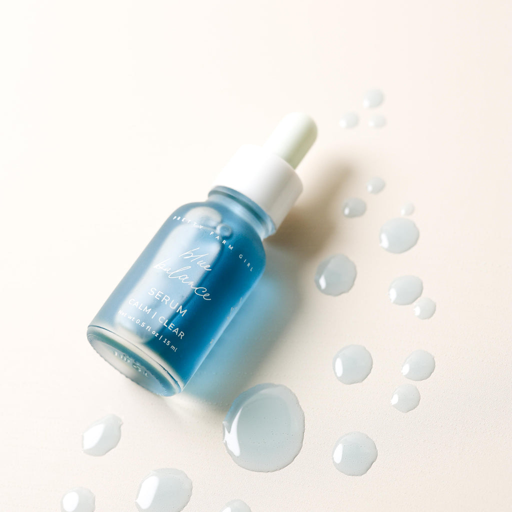 Blue face serum bottle with white dropper cap and dollops of serum