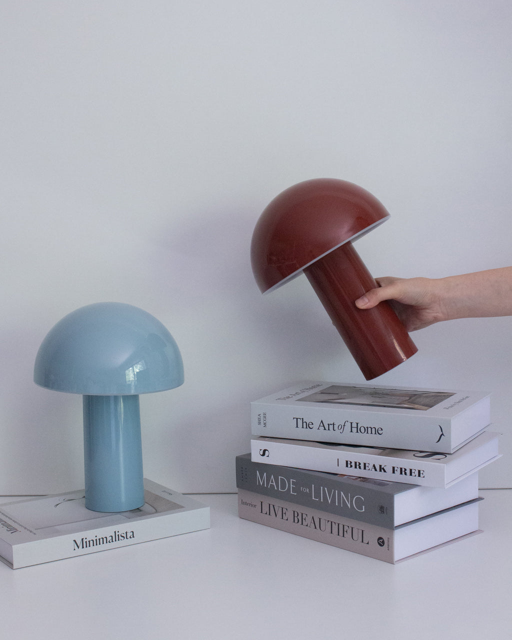 Red portable lamp with domed shade and cylindrical base, with blue lamp beside it