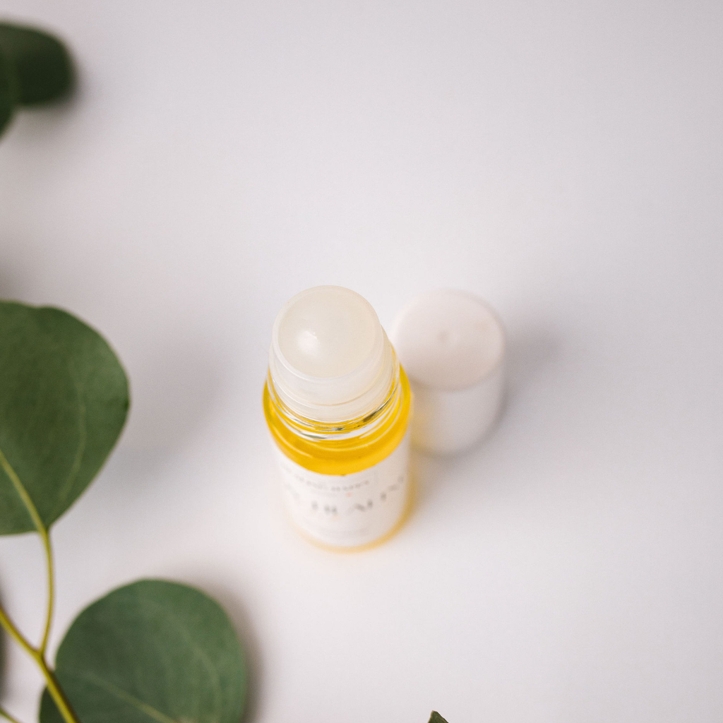 Travel-sized body healing oil bottle with open cap and an extra white cap