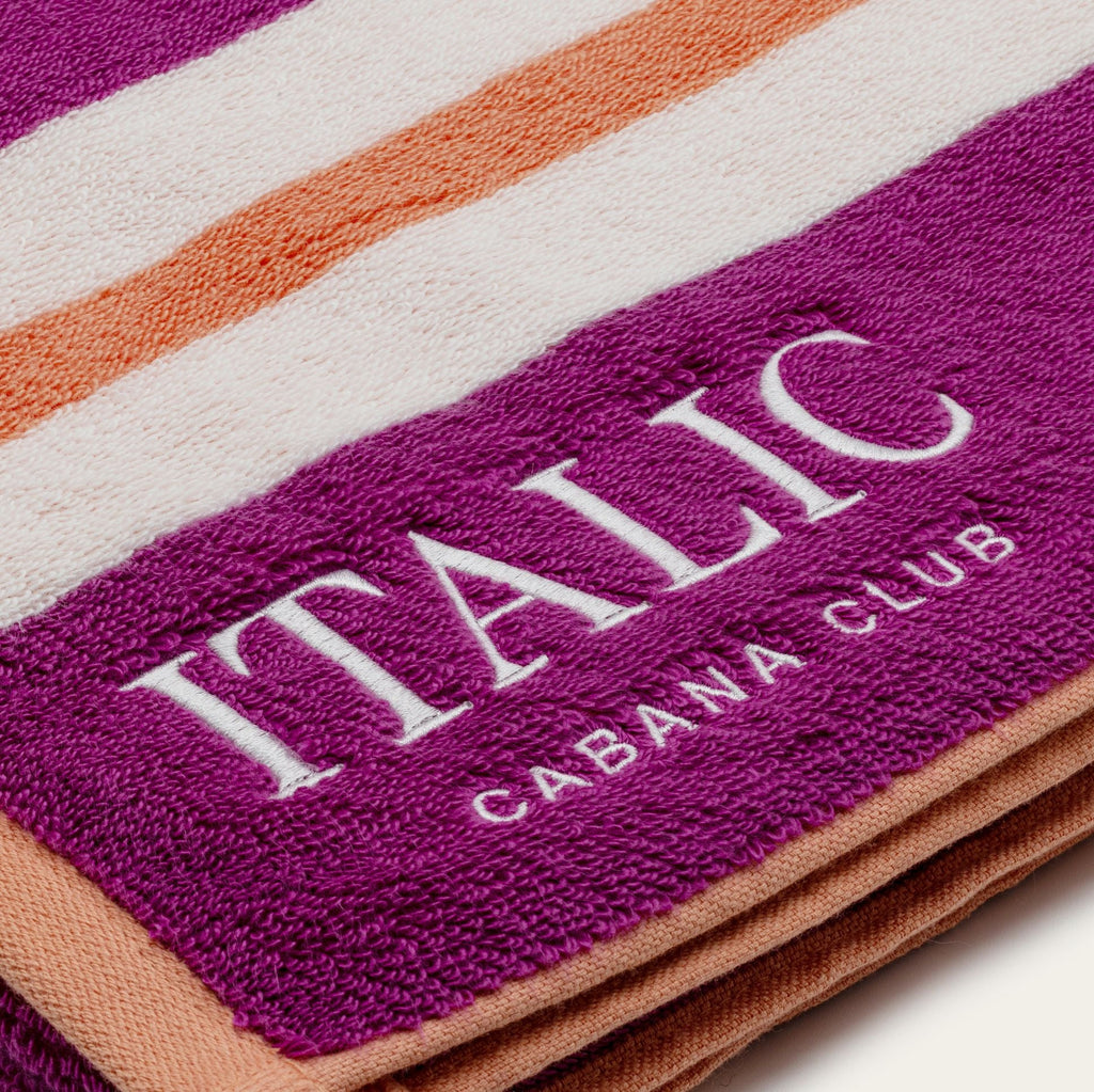 Cotton beach towel close-up with purple and cream stripes and “ITALIC” branding