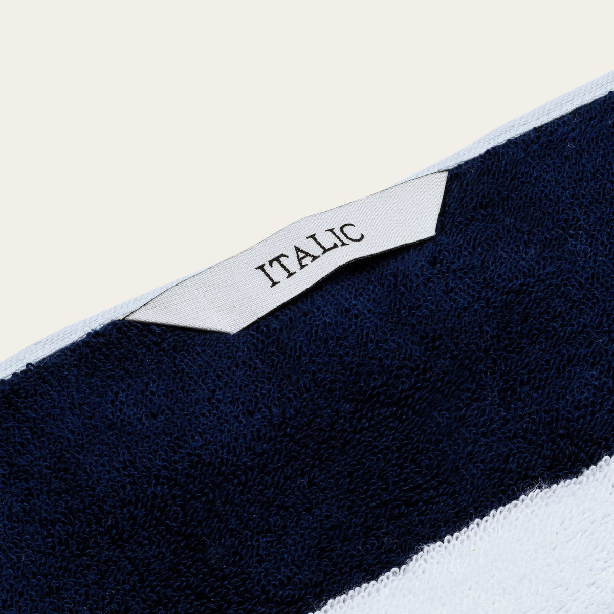Cotton beach towel corner with small woven label reading "ITALIC"