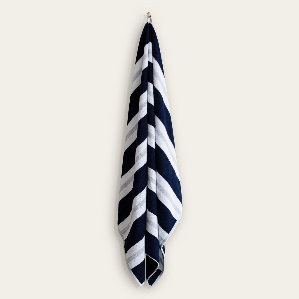 Cotton beach towel hanging with navy and white diagonal stripe pattern