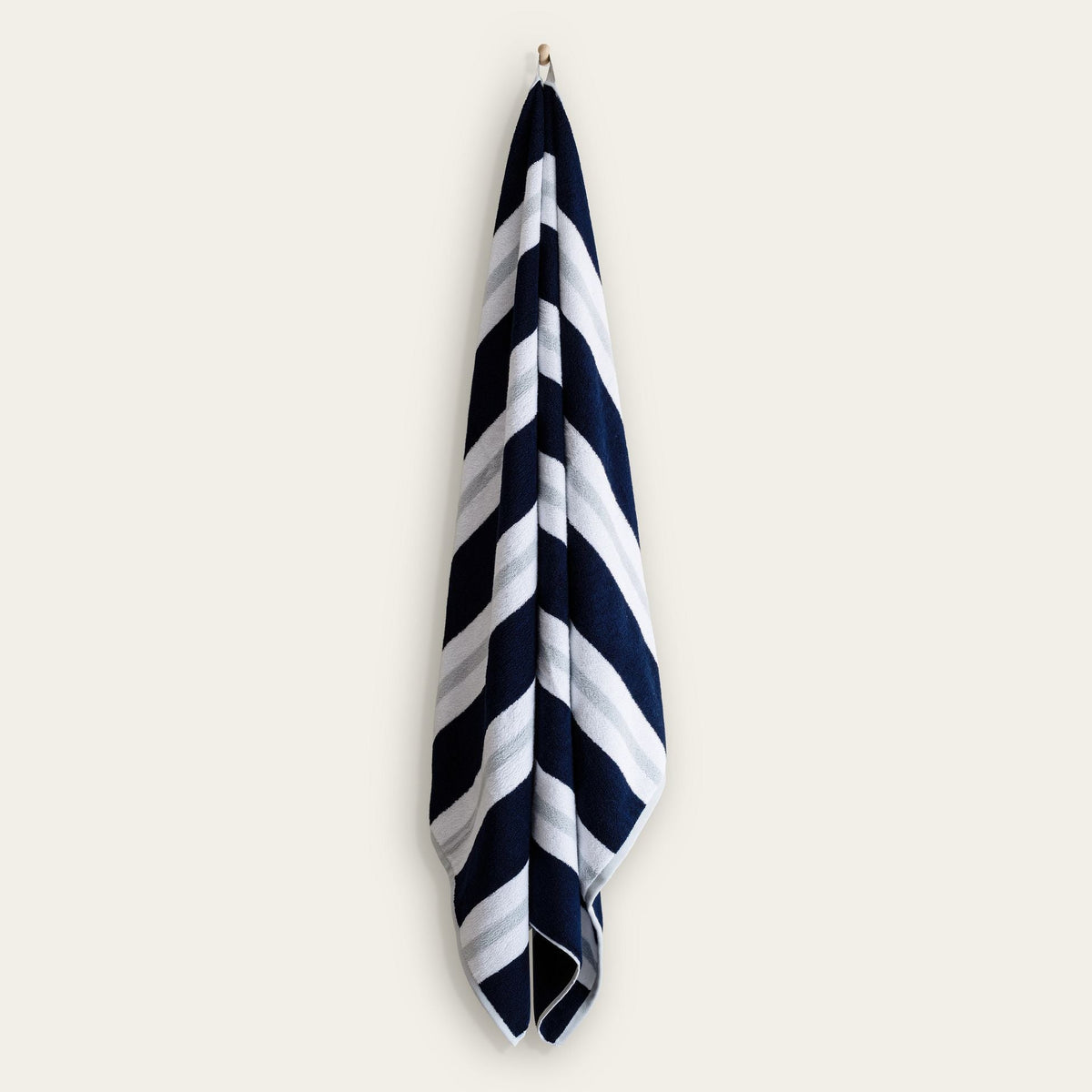 Cotton beach towel hanging with navy and white diagonal stripe pattern