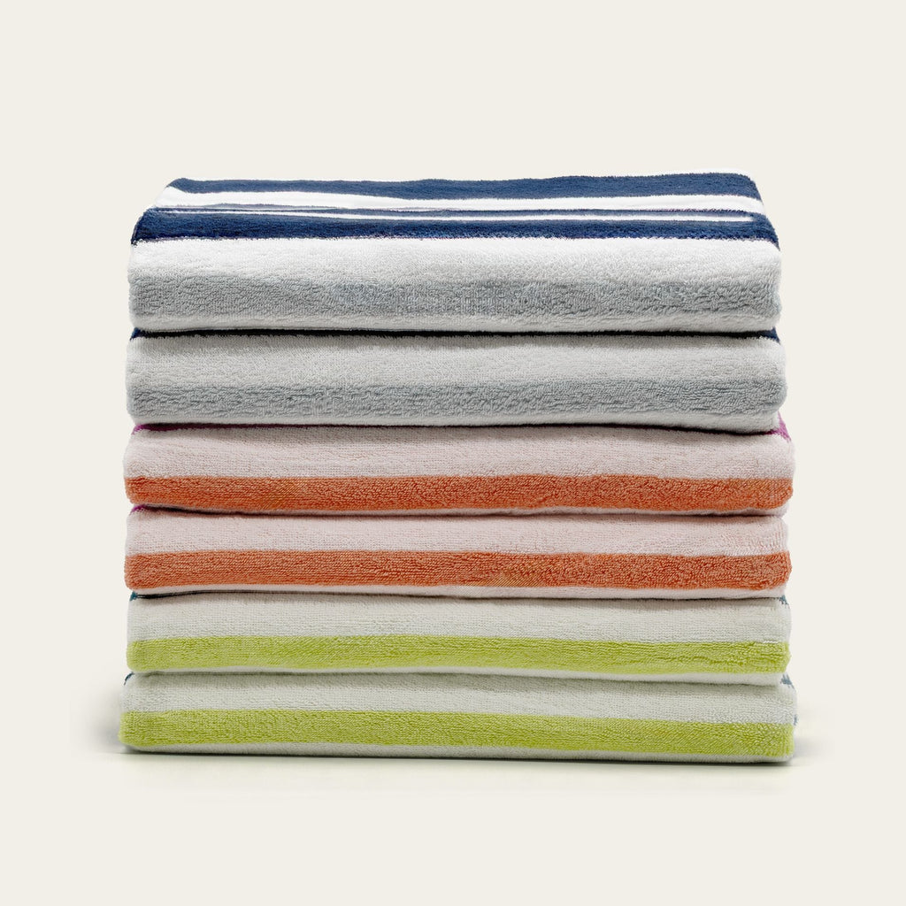 Stack of cotton beach towels in dark blue, gray, orange, and light green