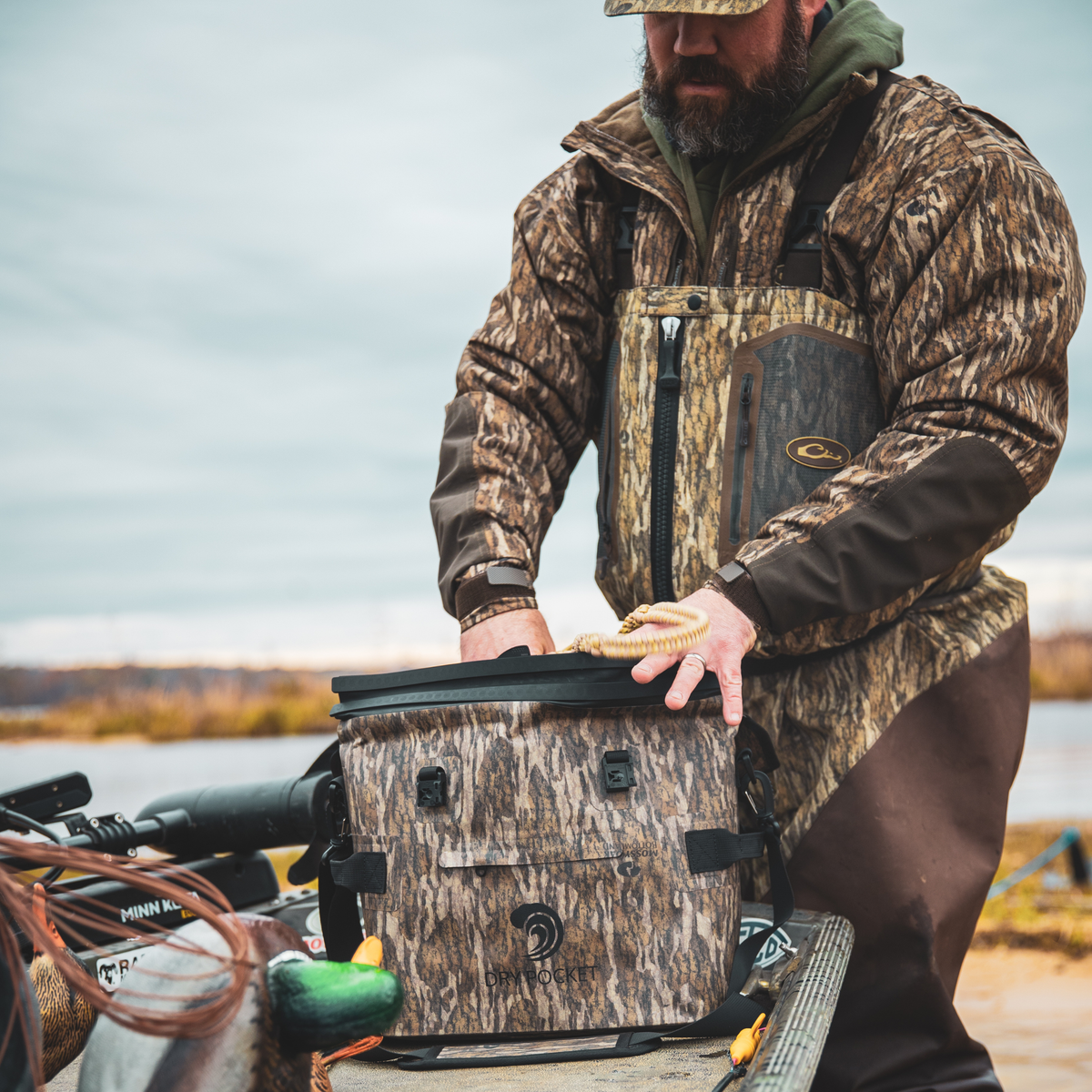 Waterproof floating cooler bag in Bottomland camo with black shoulder straps and front pocket