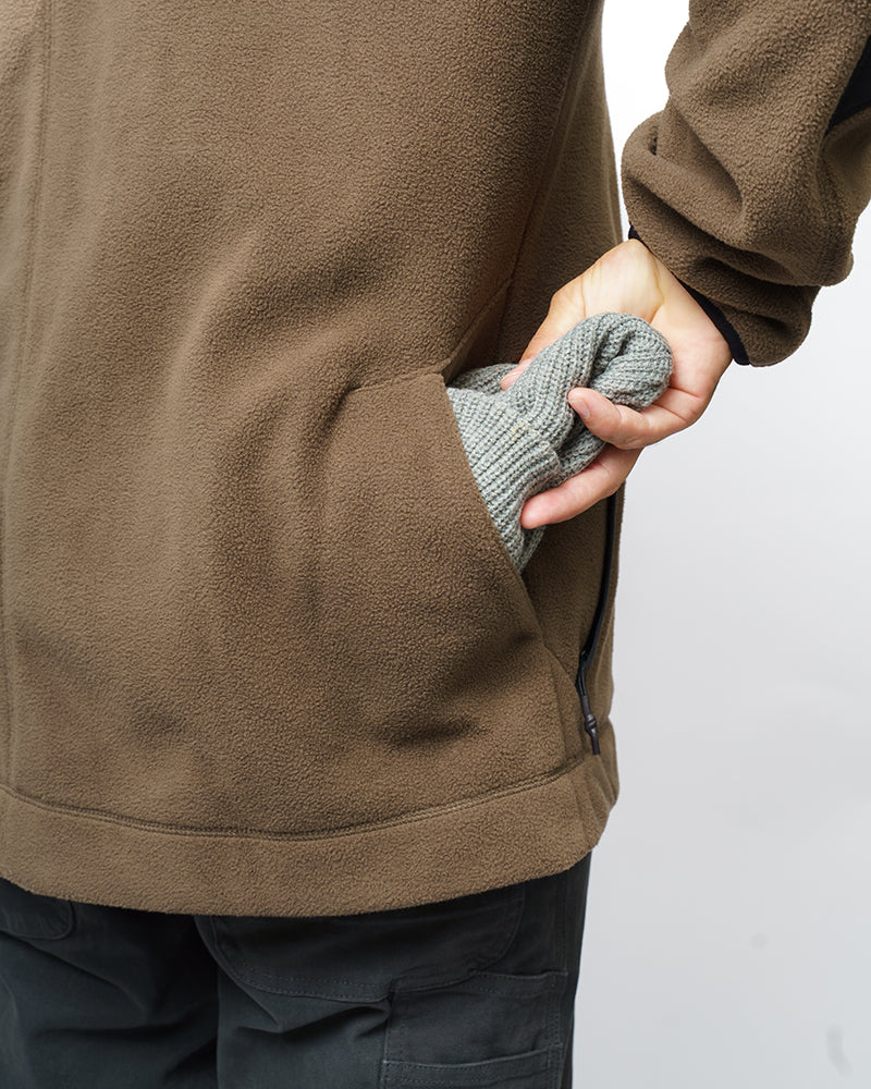 Close-up of brown fleece zip-up jacket front pocket and zipper seam.