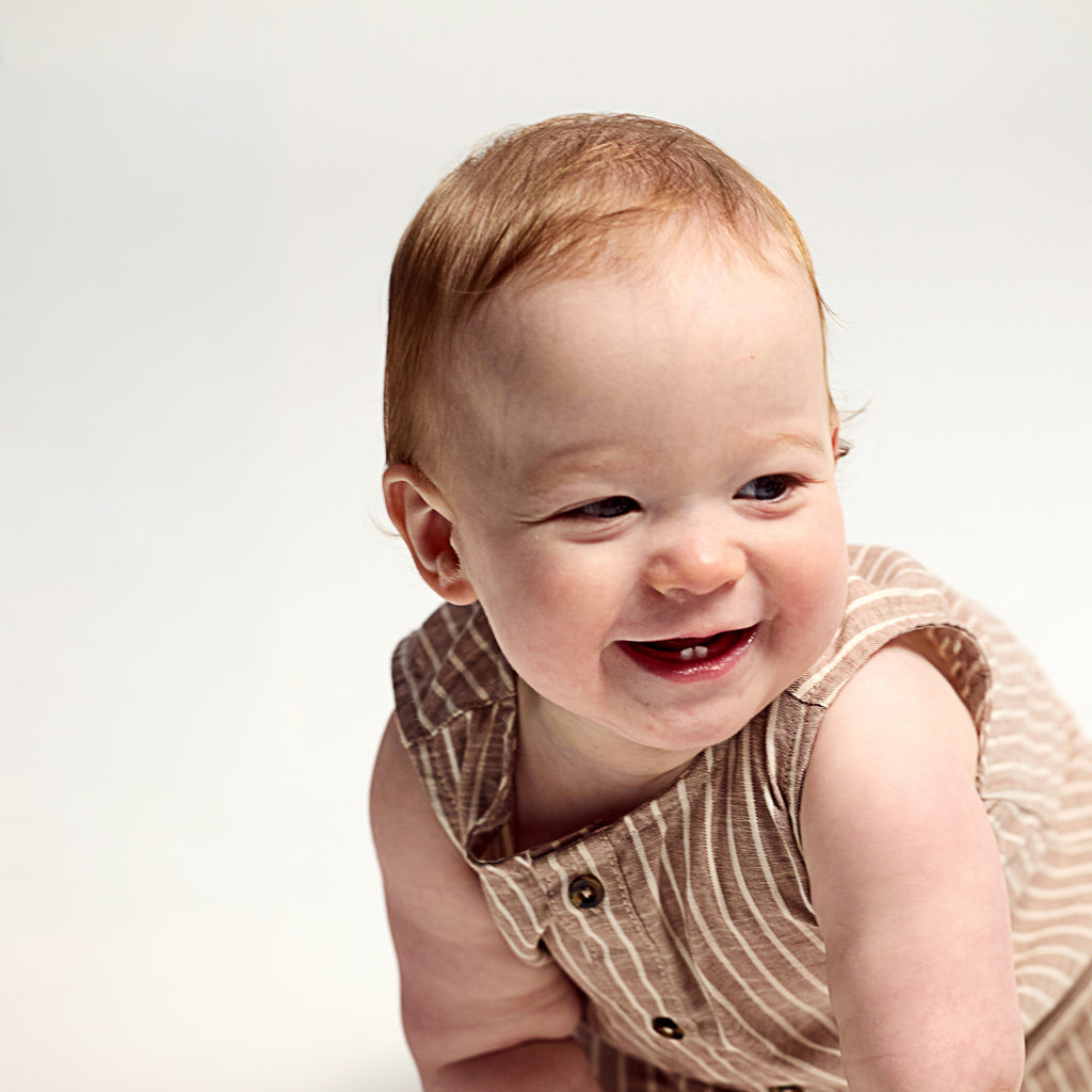 Baby in a brown striped romper with shoulder buttons