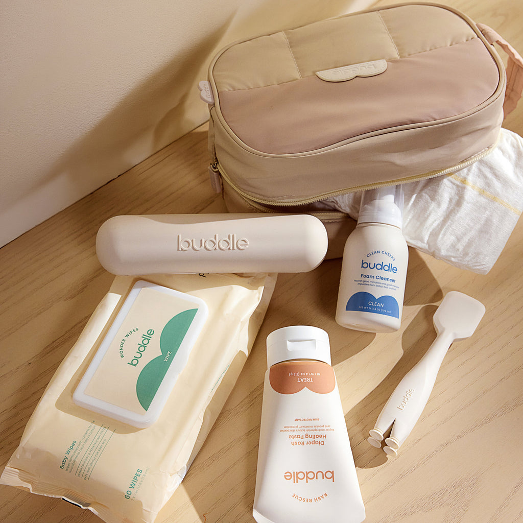 Diaper rash kit items on a table: wipes pack, bottles, and beige travel pouch