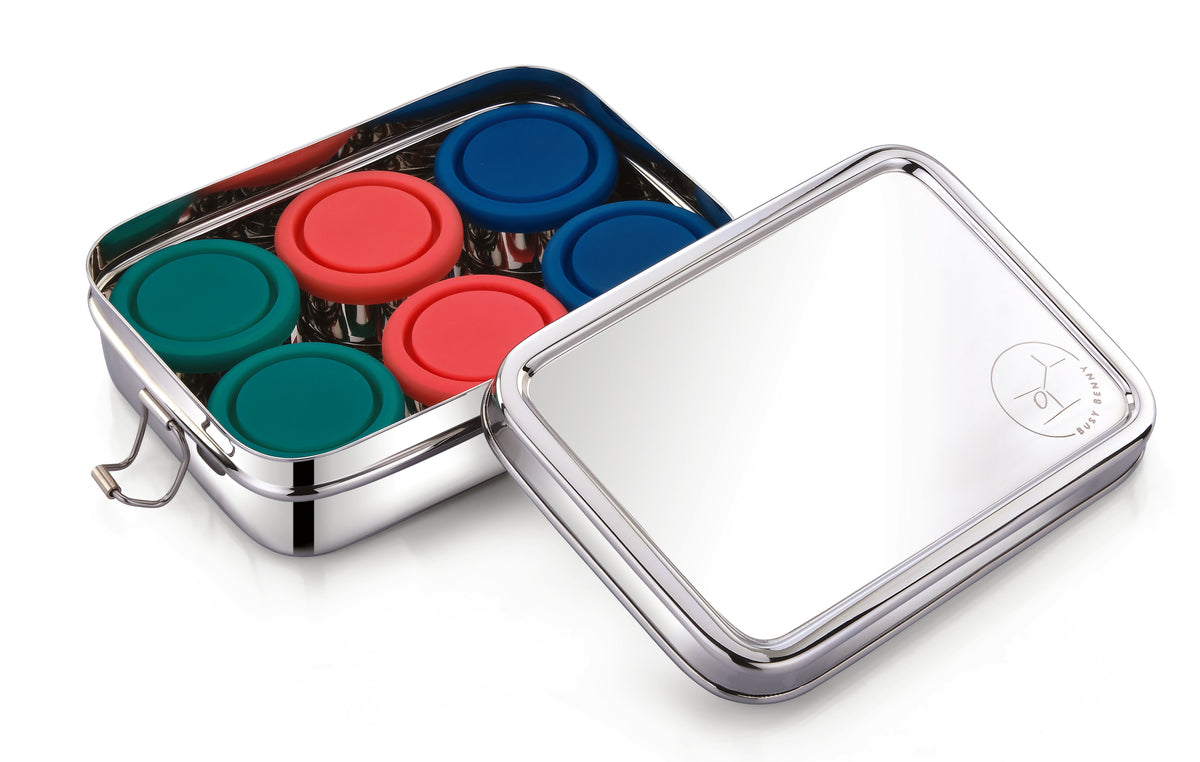 Stainless steel bento snack box with open lid, showing six colored silicone snap lids