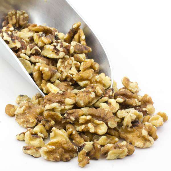Walnut halves and pieces, mixed chopped kernels in a metal scoop