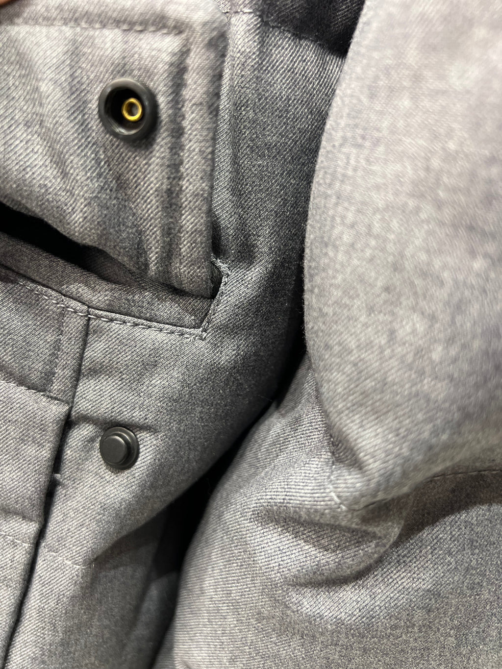 Grey coat chest area with snap button closure and pocket panel