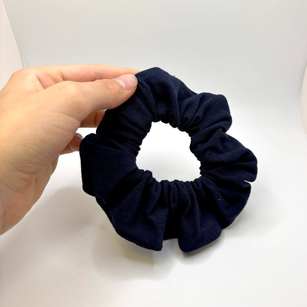 Mini navy cotton scrunchie held in hand, gathered elastic loop