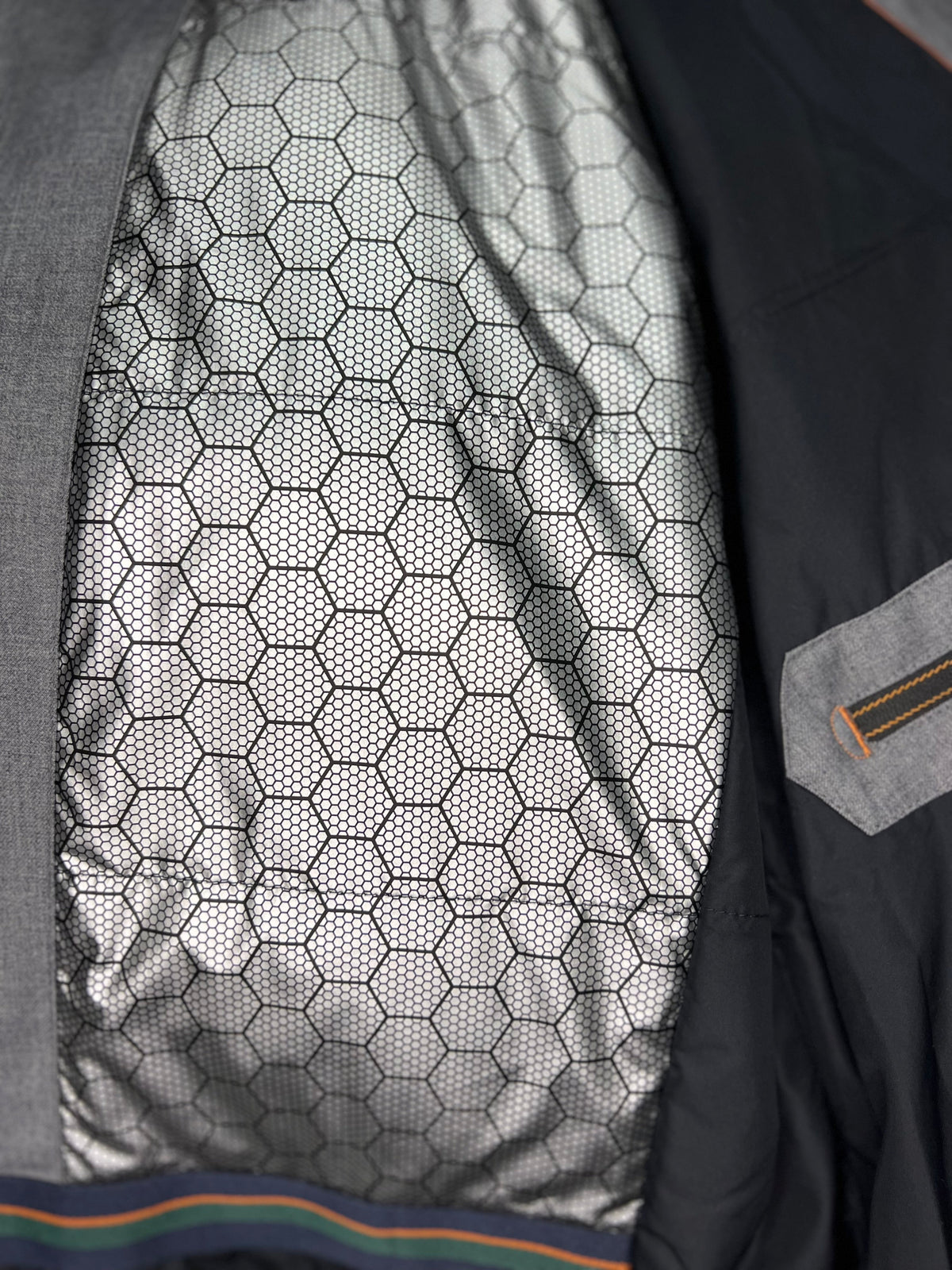 Grey coat lining with hex-pattern fabric and orange/green trim detail