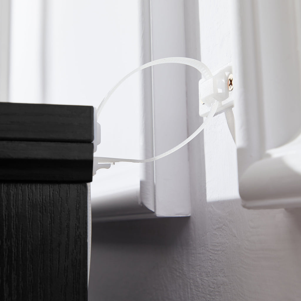 Anti-tipping strap attached to the side of a black chest of drawers