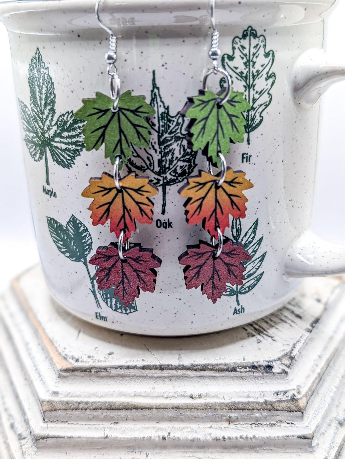 Leaf drop earrings with green, orange, and burgundy charms on silver hooks