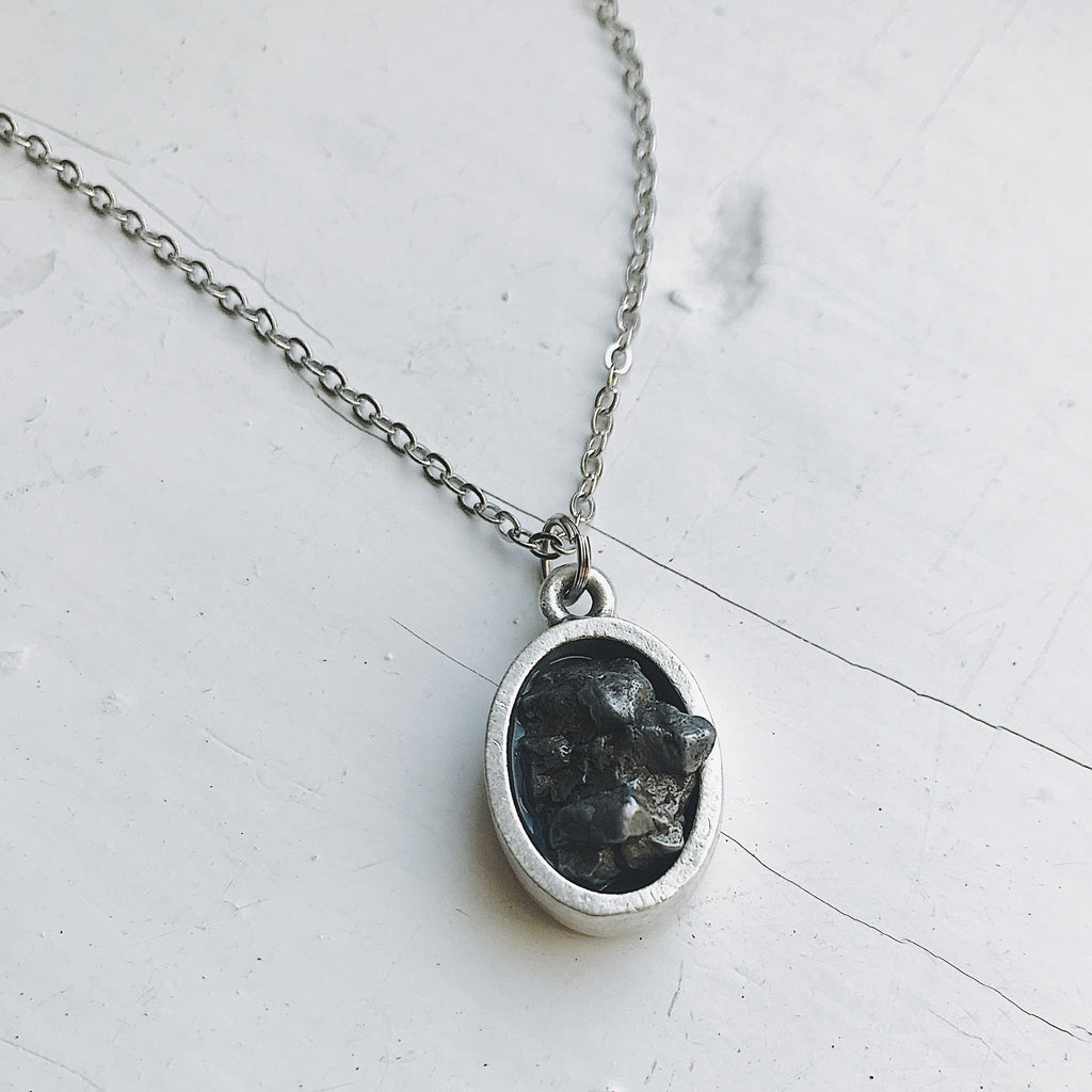 Oval meteorite pendant necklace with matte silver oval bezel and dark stone center