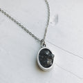 Oval meteorite pendant necklace with matte silver oval bezel and dark stone center