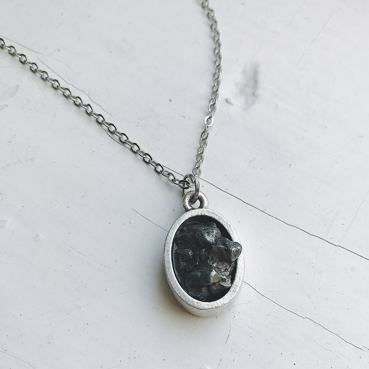 Oval meteorite pendant necklace with matte silver oval bezel and dark stone center