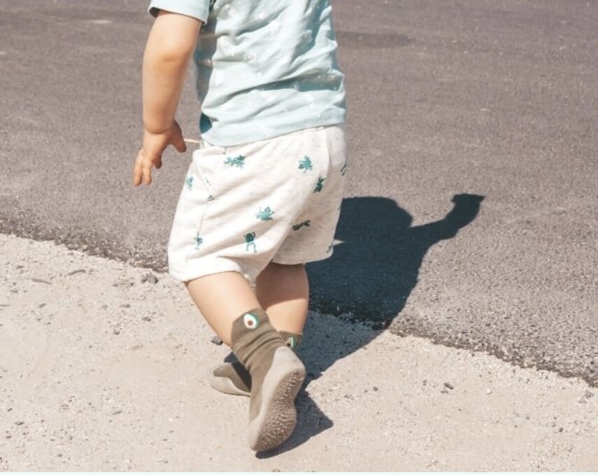 Gray barefoot sock shoes on a child’s feet outdoors.