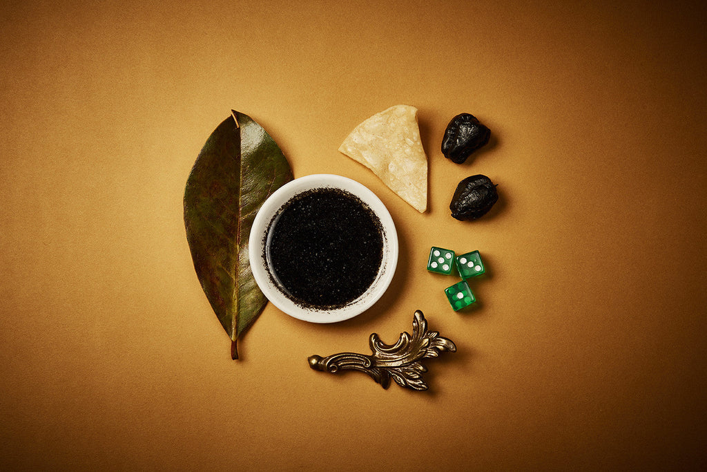 Seasoning ingredients: bowl of dark sauce with chiles, leaf, and spice accents.