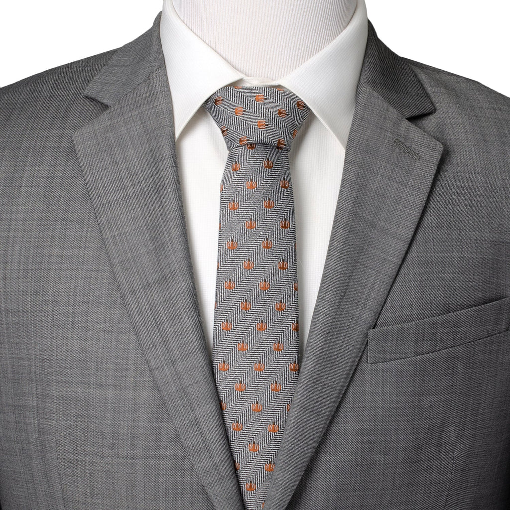 Gray suit jacket with orange pumpkin patterned herringbone necktie.