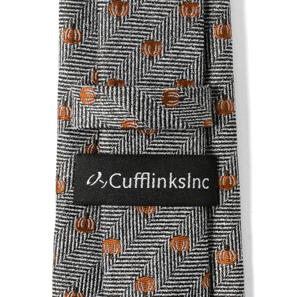 Herringbone tie close-up with orange pumpkins and “CufflinksInc” label.
