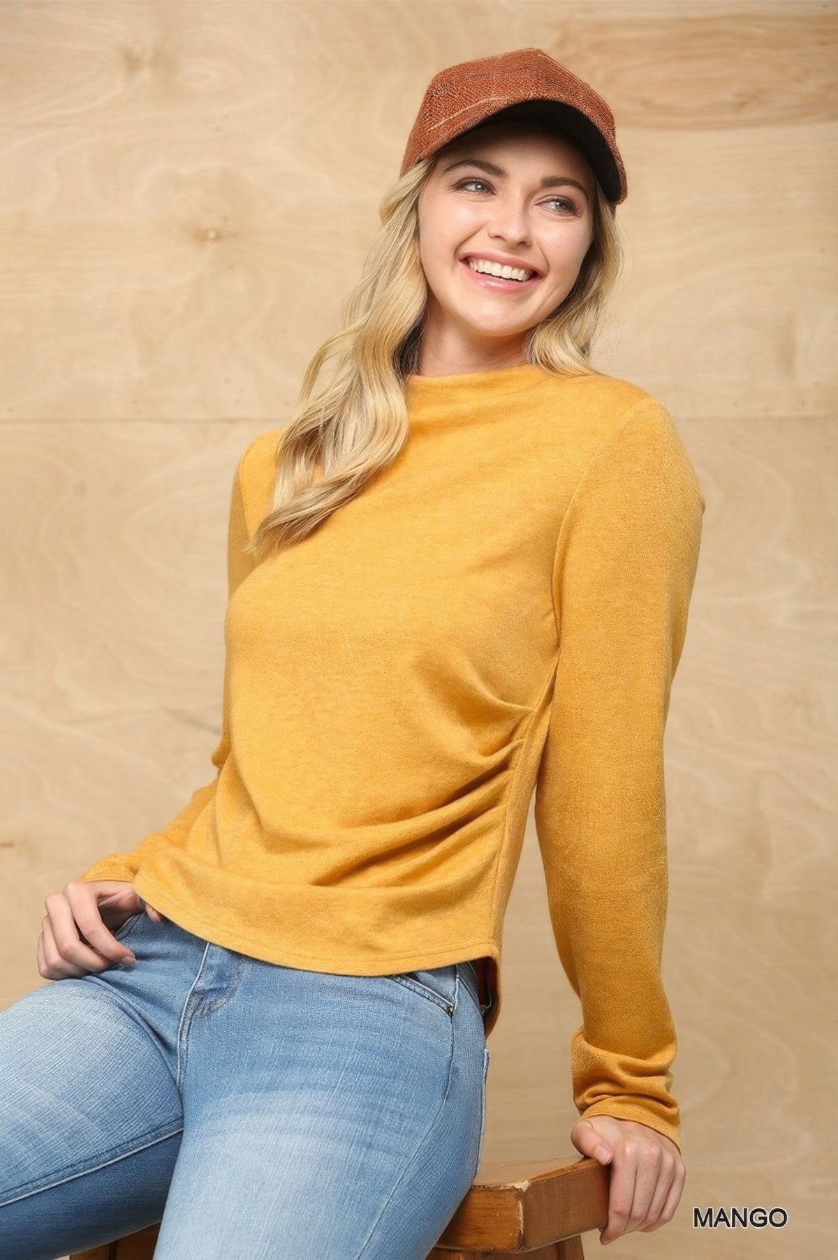 Women’s mustard mock neck knit top with side ruched hem and long sleeves.