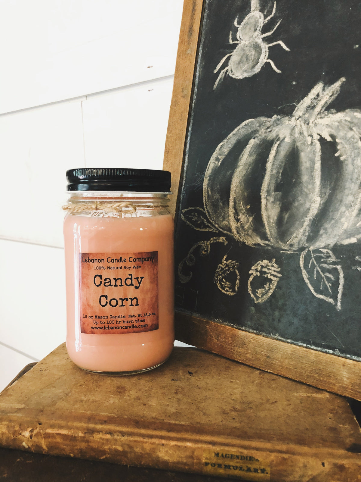 Candy corn soy candle in peach glass jar on wooden shelf