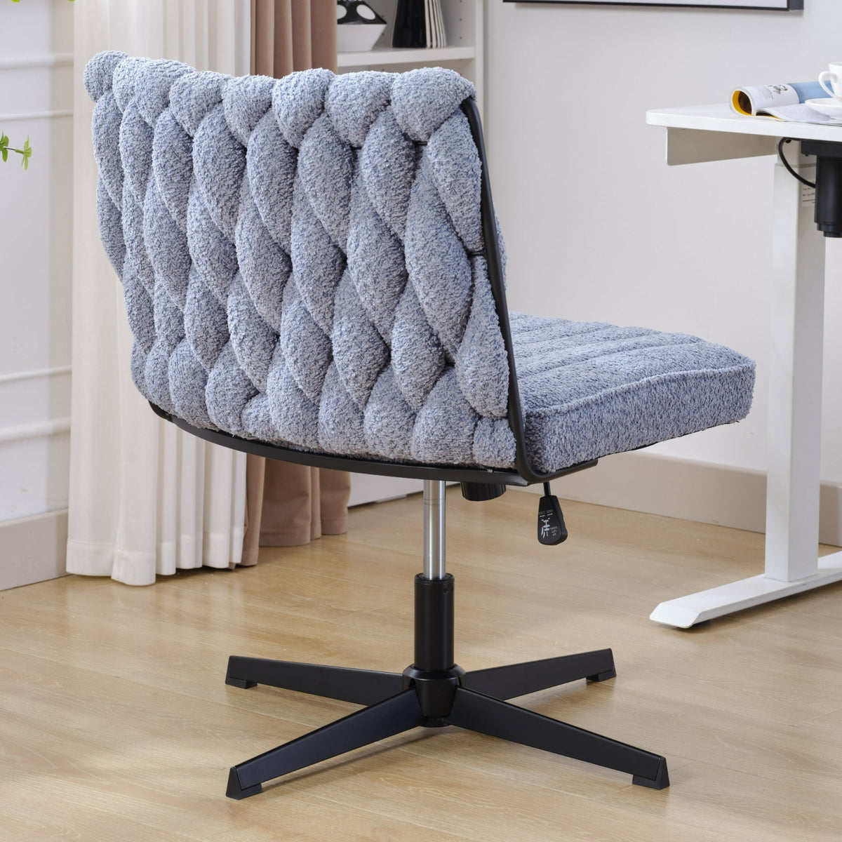 Blue armless office desk chair with tufted boucle upholstery and black star base, no wheels.