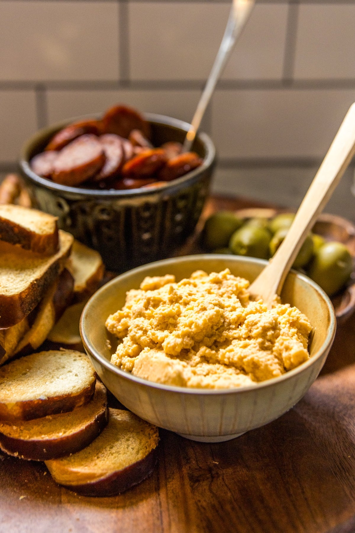 Bowl of pimento cheese spread with crackers, olives, and sliced sausage