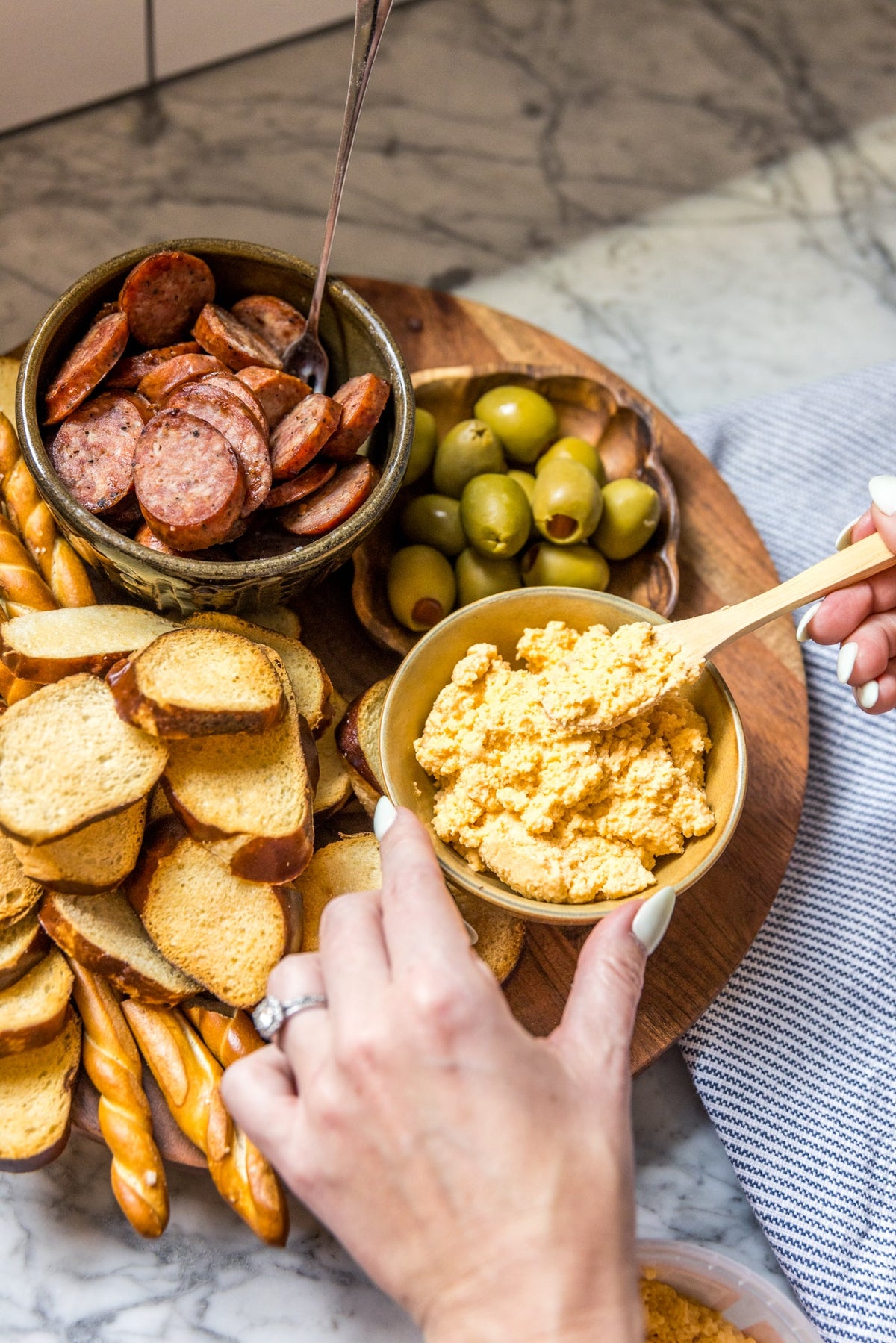 Bowl of pimento cheese spread with crackers, olives, and sliced sausage
