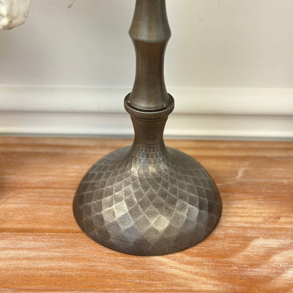 Hammered metal candle holder base with dimpled texture and slender stem