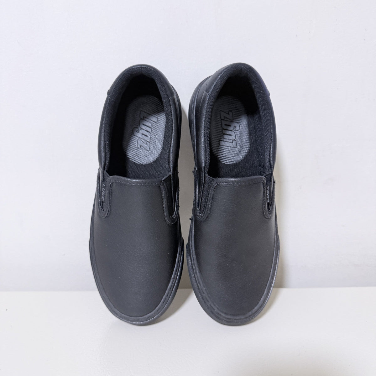 Black slip-on work shoes with padded collar and smooth upper, women's pair