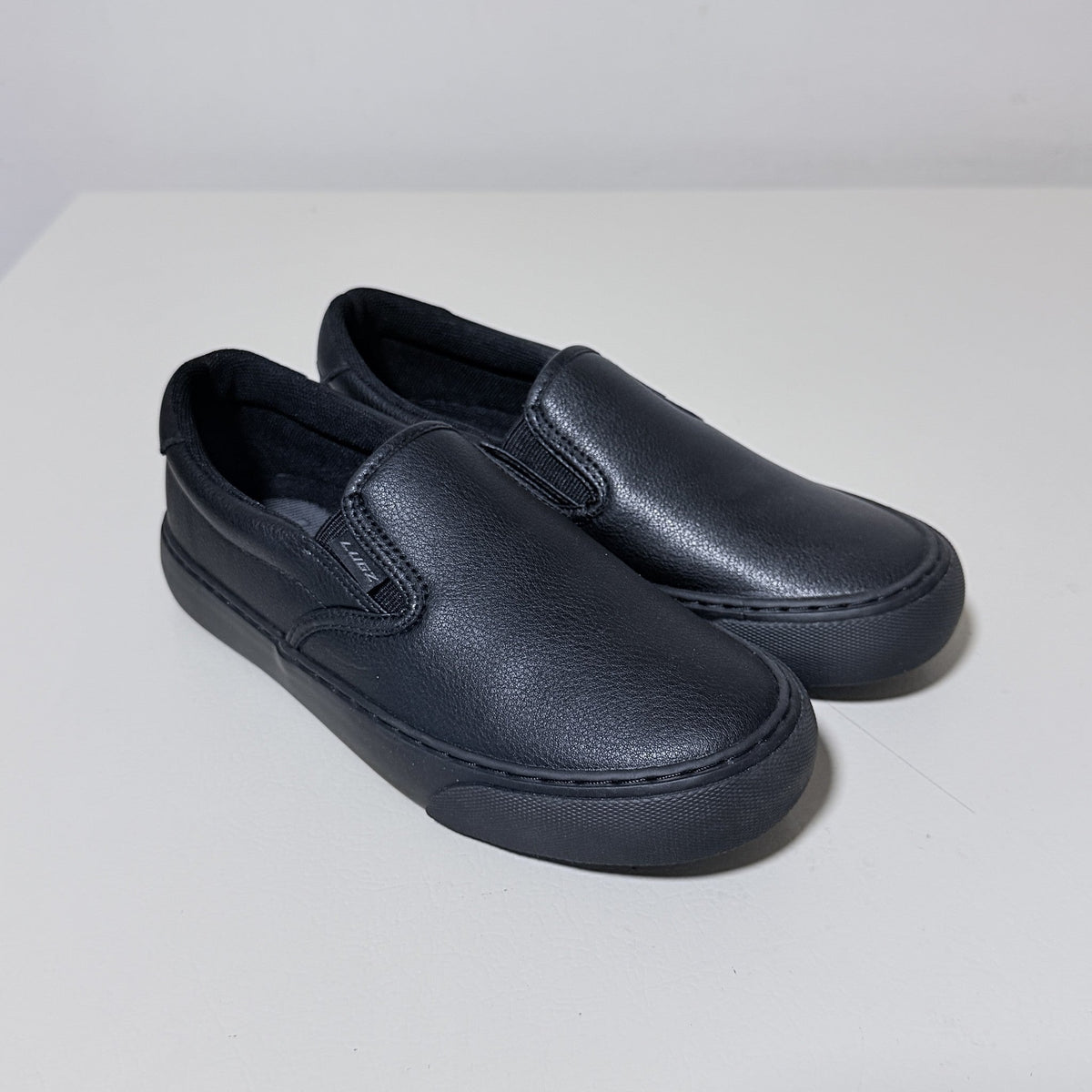 Black slip-on work shoes, angled top view with front seam detailing