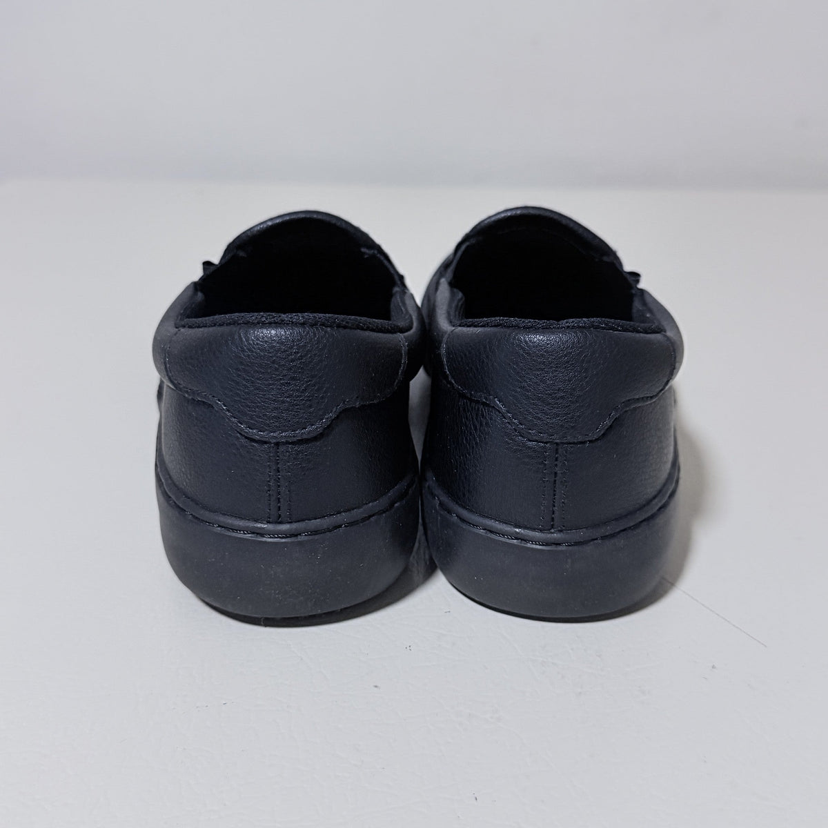 Black slip-on work shoes, rear view with heel stitching and padded collar