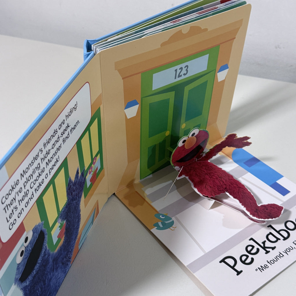 Open pop-up board book with Cookie Monster character and door scene